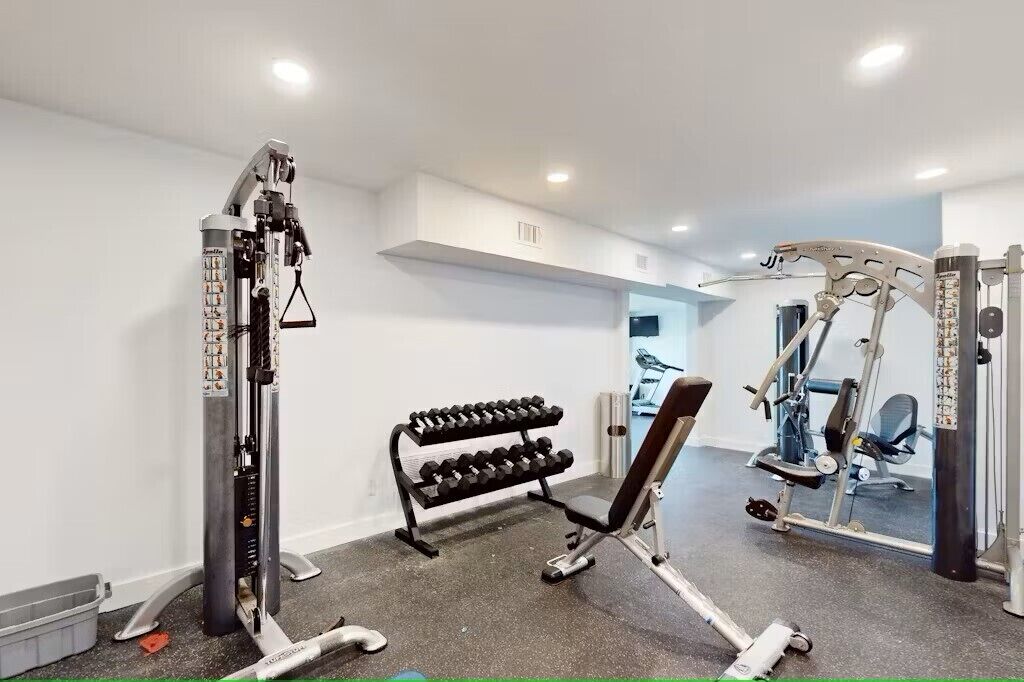 A gym with weightlifting equipment, a bench, and a rack of dumbbells.