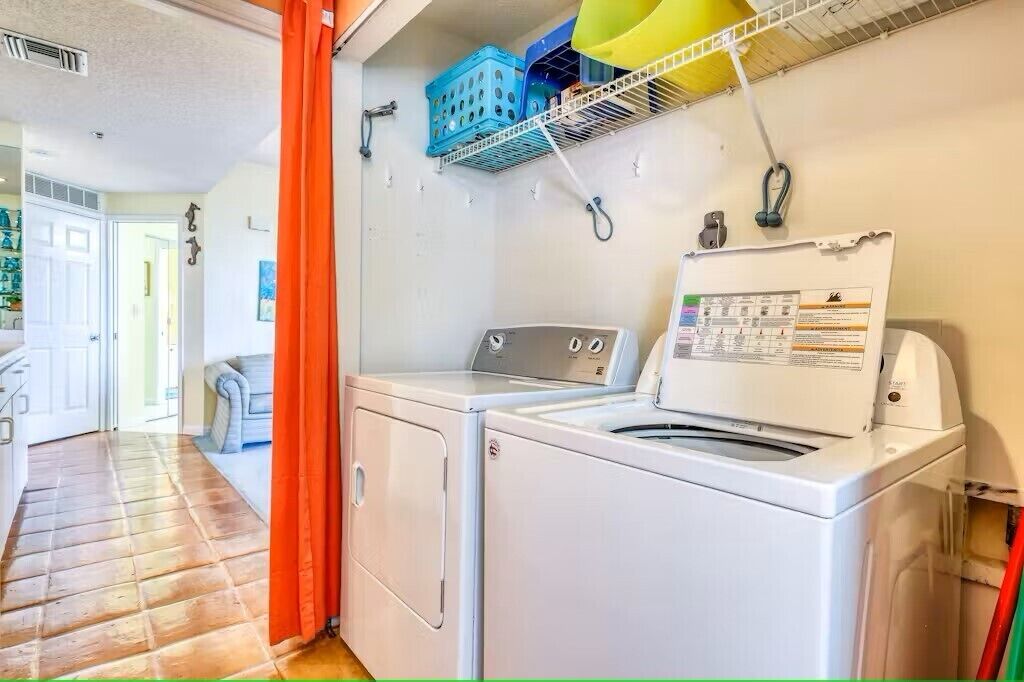 A laundry area with a washing machine and dryer, a drying rack, and a door leading to another room.