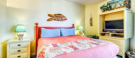 Un dormitorio con una cama, dos mesitas de noche, un televisor y un estante en la pared.