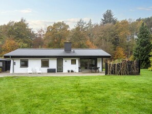 A single-story house with a tiled roof, a front door, and a patio area with outdoor furniture.