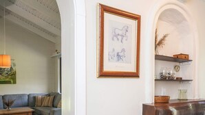 Ein Wohnzimmer mit einer Couch, einem Holztisch, einem gerahmten Kunstwerk und einem Regal mit Dekoration.