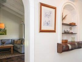 Una sala de estar con un sofá, una mesa de centro de madera, una obra de arte enmarcada y un estante con adornos.