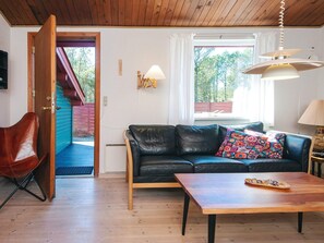 A cozy living room with a black leather sofa, a wooden coffee table, and a red leather chair.