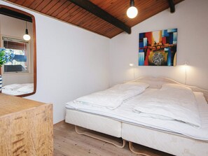 A bedroom with a bed, a wooden headboard, a bedside table, a mirror, and a painting on the wall. - 4 Person Holiday Home in Thisted (Thisted)