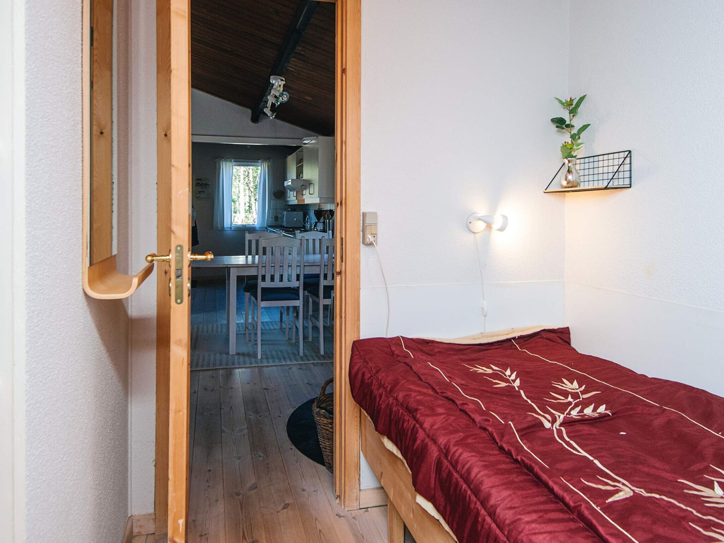 A bedroom with a wooden door leading to a dining area.