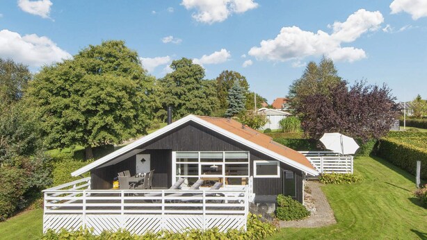 En liten, envåningsbyggnad med ett sluttande tak, en inhägnad veranda och ett stort fönster.