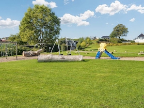 A playground with swings, a slide, and a large sculpture. - 4 Star Holiday Home in Hejls (Hejls)