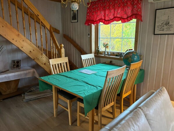 A dining area with a wooden table, chairs, and a staircase. - 7 Person Holiday Home in Tana (Tana)