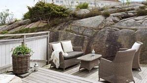 A deck with wicker furniture, a lantern, and a potted plant. - 4 Star Holiday Home in Bohus Malmon (Bohus-Malmon)