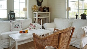 A cozy room with white furniture, a clock on the wall, and a window with a view. - 4 Star Holiday Home in Bohus Malmon (Bohus-Malmon)