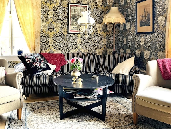 A living room with a striped sofa, a round coffee table, and patterned wallpaper. - 4 Star Holiday Home in Ljungskile (Ljungskile)