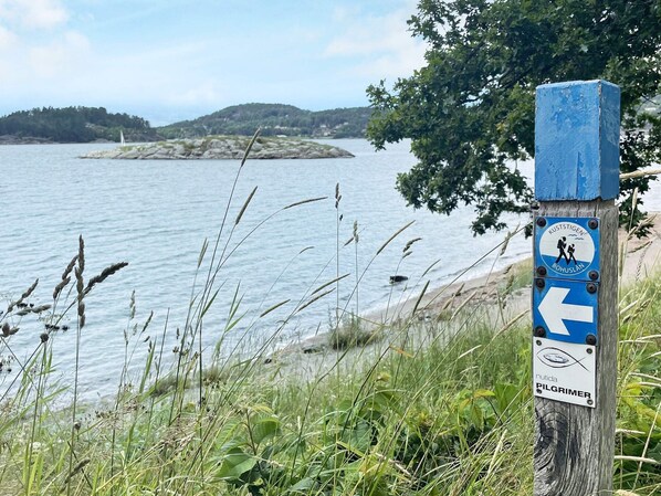 Un cartel de madera con flechas direccionales y una etiqueta para un sendero de senderismo.