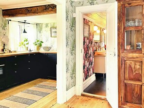 Une cuisine avec un plan de travail en bois, des meubles noirs et une fenêtre ornée de plantes.