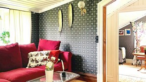 Een gezellige woonkamer met een rode bank, een glazen salontafel, een getextureerd vloerkleed en een wand met decoratieve details.