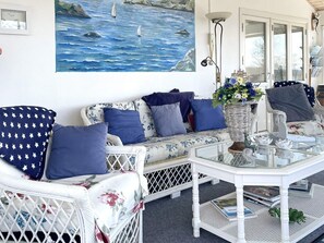 A coastal-themed living area with a sofa, chairs, a glass coffee table, and a painting of the sea. - 4 Star Holiday Home in Uddevalla (Uddevalla)