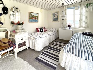 A bedroom with two beds, a dresser, a chair, a window with curtains, and a painting on the wall. - 4 Star Holiday Home in Uddevalla (Uddevalla)