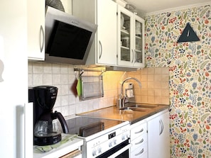 A kitchen with a microwave, stove, sink, and a cabinet with glass doors. - 4 Star Holiday Home in Uddevalla (Uddevalla)