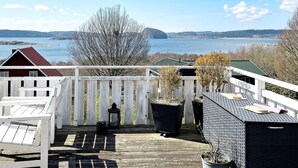 A wooden deck with a white railing, overlooking a body of water with distant landforms. - 4 Star Holiday Home in Uddevalla (Uddevalla)