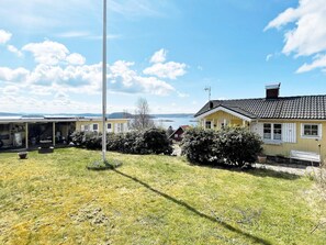 A residential property with a grassy yard, a white pole, and a yellow house with a tiled roof. - 4 Star Holiday Home in Uddevalla (Uddevalla)