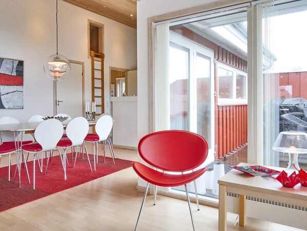 Un intérieur moderne avec un coin repas, des chaises rouges et une grande fenêtre.