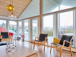 Une pièce spacieuse avec de grandes fenêtres, des meubles en bois et un plafond orné de poutres en bois.