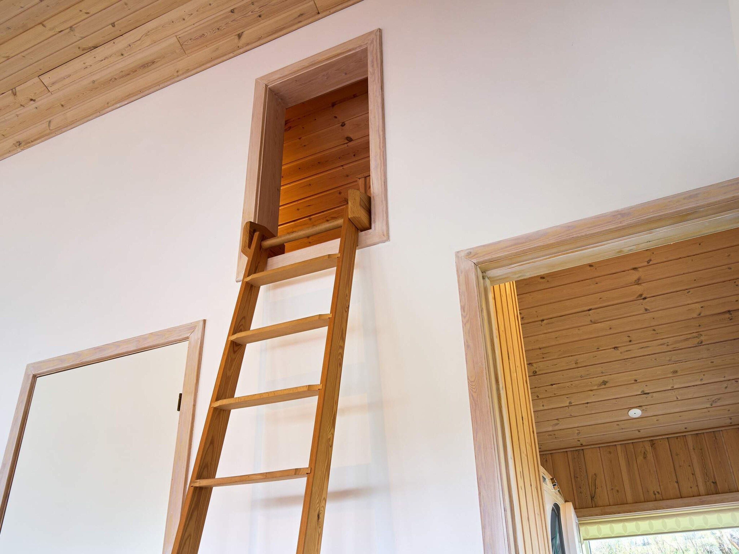 Een houten ladder die tegen een muur staat, met een klein raam.