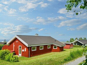 Un bâtiment rouge avec un toit en pente, une porte et des fenêtres.