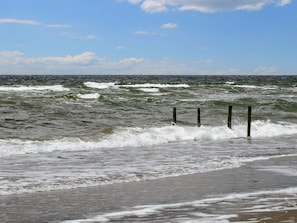 A beach with waves, a clear sky, and a wooden structure in the water. - 5 Star Holiday Home in Romo (Rømø)