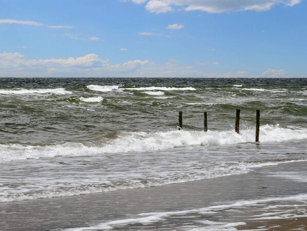 En strand med vågor som slår in mot land och en klar himmel.