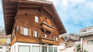 Un chalet traditionnel en bois, doté d’un toit à pente, de nombreuses fenêtres et d’un balcon.
