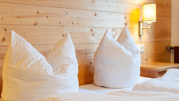 Une chambre d’hôtel avec un mur en bois, deux fauteuils en forme de sac en tissu blanc et une table de chevet avec une lampe.