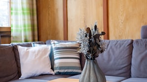 Un salon moderne avec un canapé gris, une table basse en bois et un vase gris contenant des fleurs séchées.