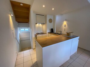 Eine moderne Küche mit Holztresen, weißen Schränken, einem eingebauten Herd und einem Spülbecken.