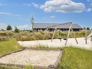 A sandy outdoor area with a wooden swing set, a tire swing, and a picnic table. - 5 Star Holiday Home in Romo (Rømø)