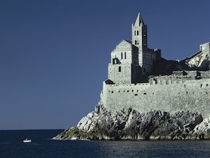 Eine historische Steinburg mit einem markanten Turm, gelegen an einer felsigen Küstenlinie mit dem Meer im Vordergrund.