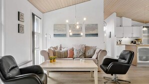 A modern living room with a sofa, two chairs, a coffee table, and artwork on the walls. - 4 Star Holiday Home in Hals (Hals)