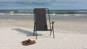 A beach chair on a sandy beach with waves in the background. - 6 Person Holiday Home in Mellbystrand (Mellbystrand)