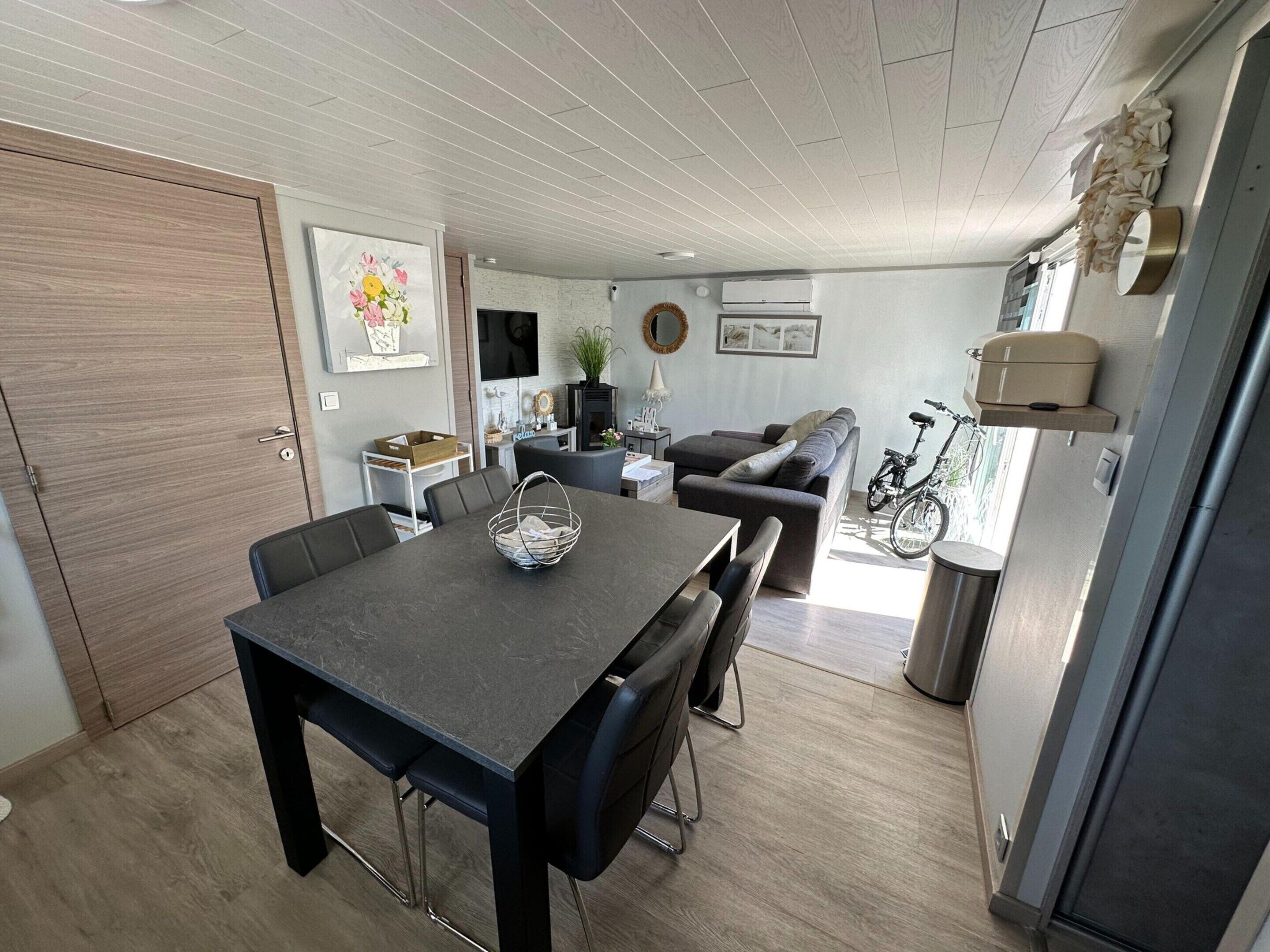 A modern living space with a dining area, sofa, and bicycle.