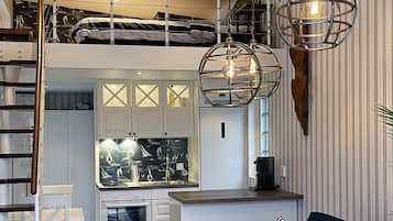 Um espaço de estar estilo loft, com cozinha, mesa de jantar e sofá.