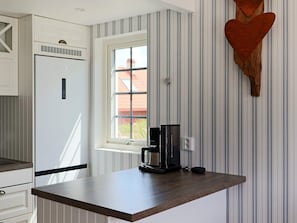 Una cocina con refrigerador empotrado, una ventana y una cafetera sobre la encimera.