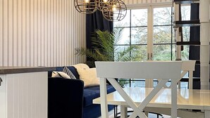 Un soggiorno moderno con un divano blu scuro, un tavolo da pranzo bianco e un lampadario particolare.