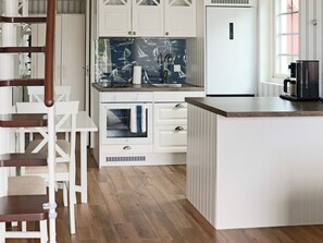 A kitchen with white cabinetry, a wooden floor, and a coffee maker on the counter. - 4 Star Holiday Home in Varberg (Varberg)