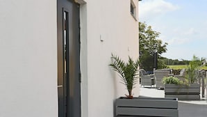 A modern outdoor patio with a white wall, a door, and outdoor furniture. - 4 Star Holiday Home in Varberg (Varberg)