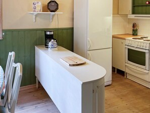 Une cuisine avec un plan de travail blanc, une machine à café, une bouilloire et une cuisinière.