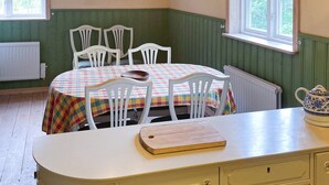 A dining area with a table set for four, a wooden cutting board, and a white cabinet with drawers. - 4 Star Holiday Home in Svangsta (Svangsta)