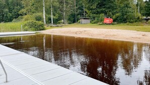 A swimming pool with a wooden deck, surrounded by trees and a small shed. - 4 Star Holiday Home in Svangsta (Svangsta)