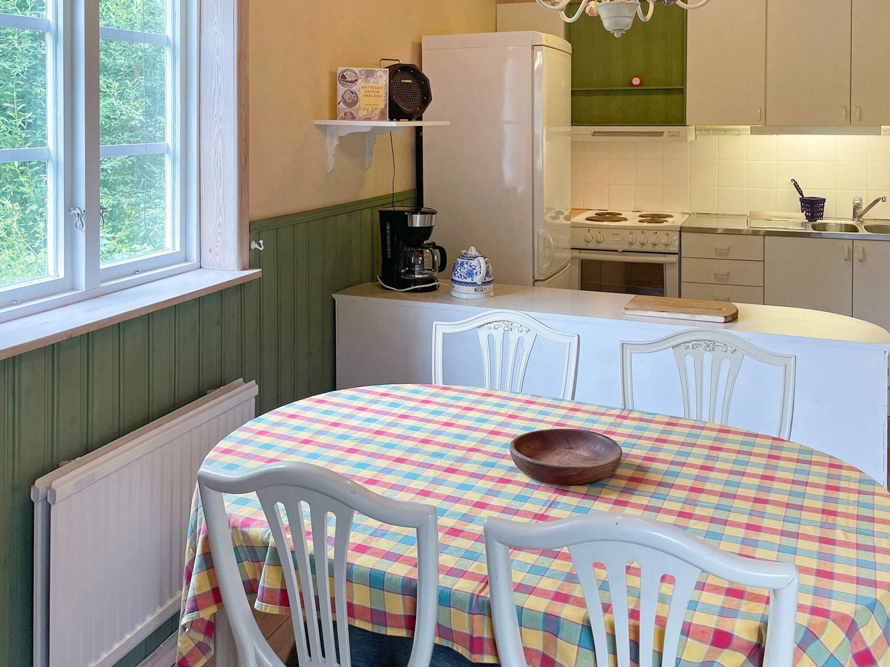 Eine Küche mit einem runden Tisch, weißen Stühlen, einer Kaffeemaschine und einem Herd.