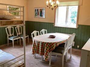 A room with bunk beds, a dining table with chairs, a chandelier, and a window with a view. - 4 Star Holiday Home in Svangsta (Svangsta)