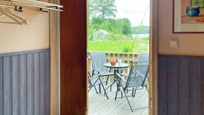 Ein Zimmer mit einer Holztür, die auf eine Terrasse mit Tisch und Stühlen führt.