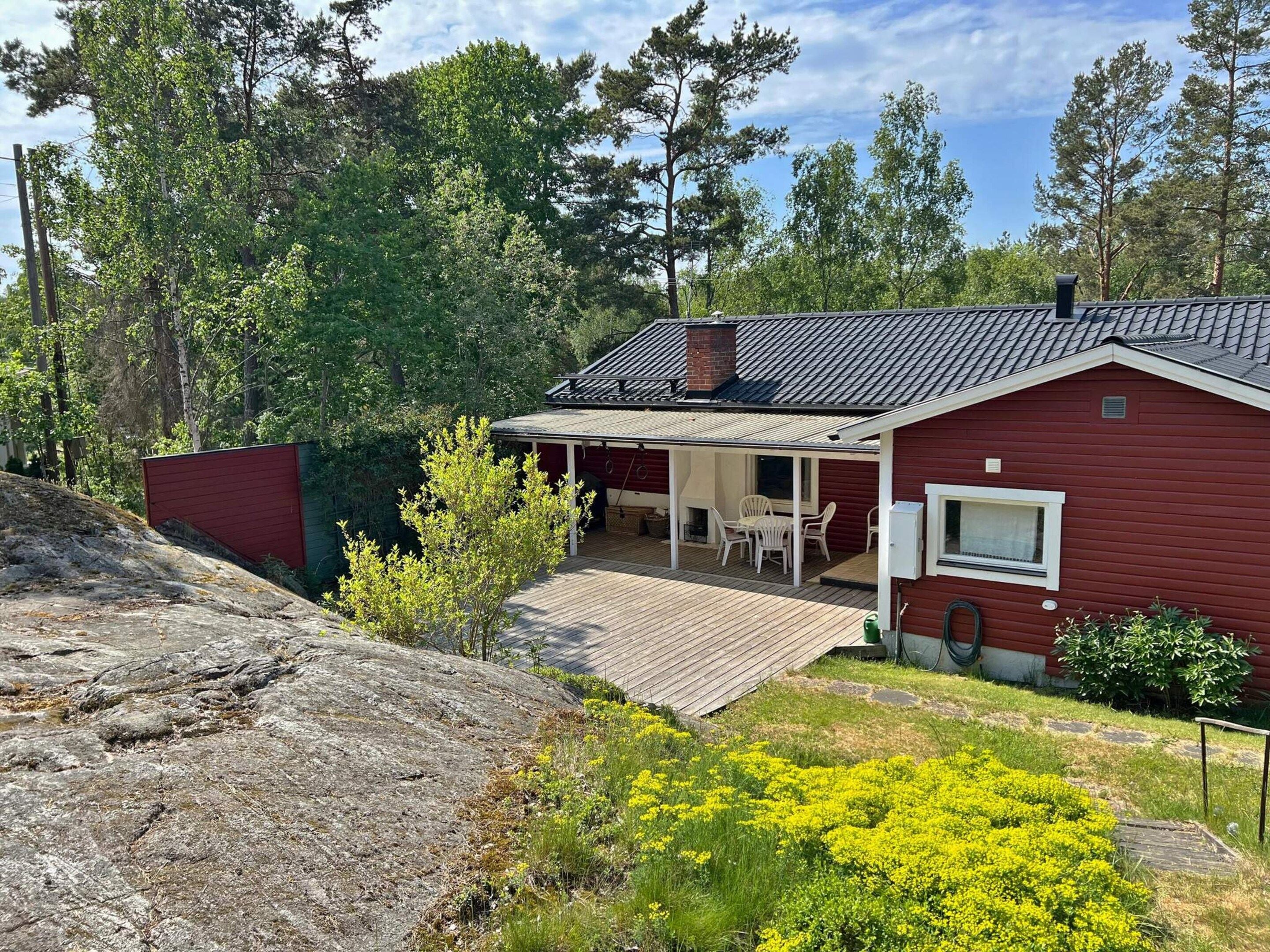 A red house with a covered patio and a small garden.